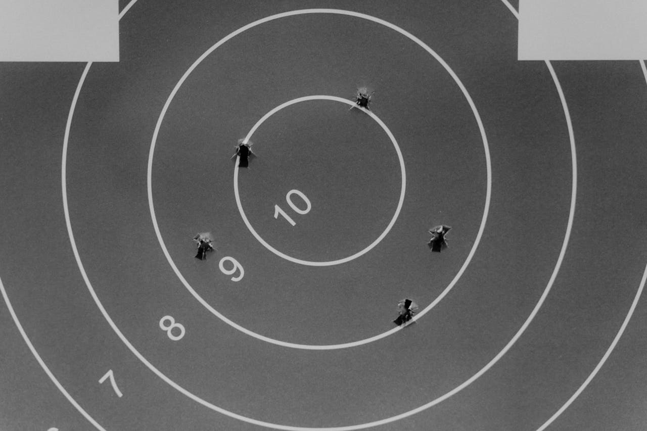 Home Black and white image of a shooting target with bullet holes.